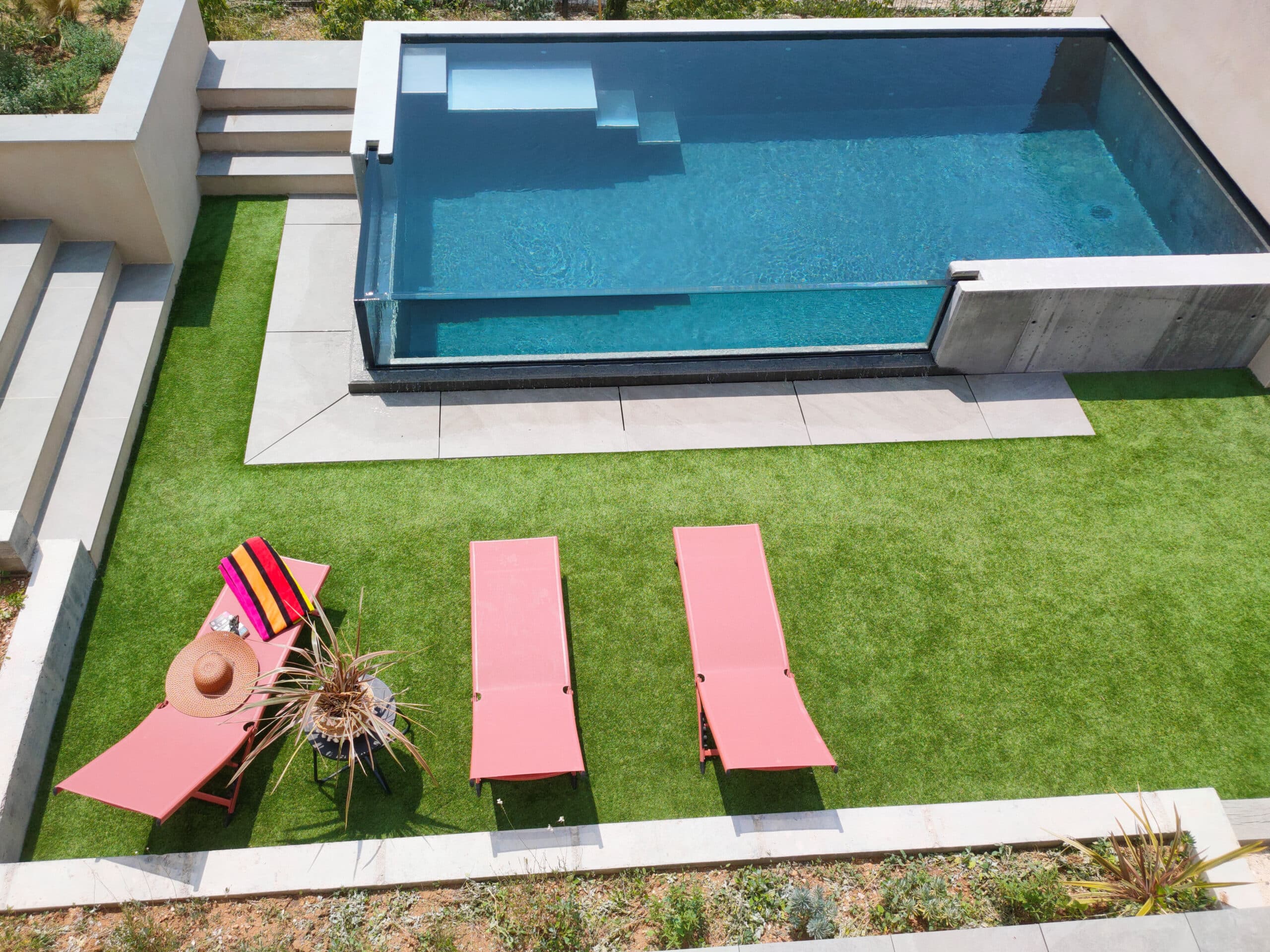 Scanzi Piscines confectionne votre piscine à débordement avec paroi vitrée.